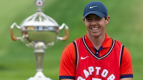 Rory McIlroy laughs as he puts on a Toronto Raptors jersey during the trophy presentation at the Canadian Open golf championship in Ancaster, Ontario, on Sunday, June 9, 2019. (Adrian Wyld/The Canadian Press via AP)
