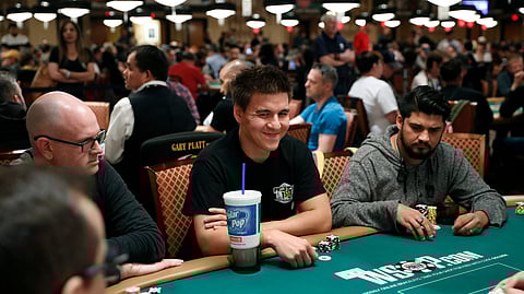 In this June 24, 2019, file photo, “Jeopardy!” champion and professional sports gambler James Holzhauer, center, plays in a tournament at the World Series of Poker in Las Vegas.