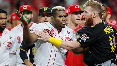 Cincinnati Reds' Yasiel Puig (66) is restrains by Pittsburgh Pirates third baseman Colin Moran (19) during the ninth inning of a baseball game Tuesday, July 30, 2019, in Cincinnati. (AP Photo/John Minchillo)