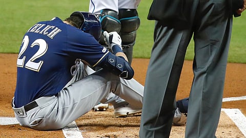 Milwaukee Brewers' Christian Yelich (22) sits on the ground after an injury while at bat as Miami Marlins catcher Jorge Alfaro, rear, and home plate umpire Kerwin Danley look on during the first inning of a baseball game, Tuesday, Sept. 10, 2019, in Miami. (AP Photo/Wilfredo Lee)