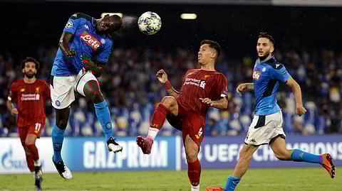 Napoli's Kalidou Koulibaly, left, heads the ball as Liverpool's Roberto Firmino tries to stop him during the Champions League Group E soccer match between Napoli and Liverpool, at the San Paolo stadium in Naples, Italy, Tuesday, Sept. 17, 2019.