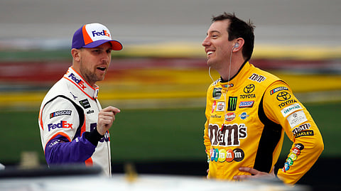 FILE - In this March 1, 2019, file photo, drivers Denny Hamlin, left, and Kyle Busch talk in pit lane before qualifying for the NASCAR Cup Series auto race at Las Vegas Motor Speedway in Las Vegas. Hamlin has all the momentum headed into the third round of NASCAR's playoffs, which start Sunday at Martinsville Speedway. But hot on his bumper are his Joe Gibbs Racing teammates, regular season champion Kyle Busch and Martin Truex Jr., who leads the series with six wins this season.(AP Photo/John Locher, File)