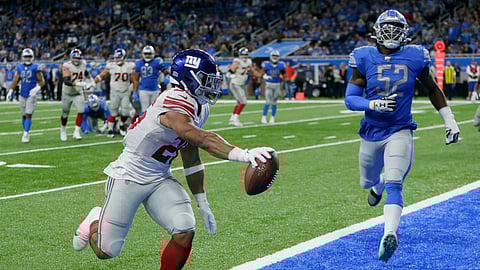 New York Giants running back Saquon Barkley (26) runs ahead of Detroit Lions outside linebacker Christian Jones (52) and scores during the second half of an NFL football game, Sunday, Oct. 27, 2019, in Detroit.