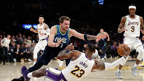 Los Angeles Lakers' LeBron James (23) recovers a loose ball under Dallas Mavericks' Luka Doncic (77) during the first half of an NBA basketball game Sunday, Dec. 1, 2019, in Los Angeles.