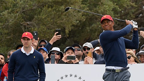USA's Patrick Cantlay, left, watches as captain Tiger Woods tees off during a practice session ahead of the President's Cup Golf tournament in Melbourne, Tuesday, Dec. 10, 2019.