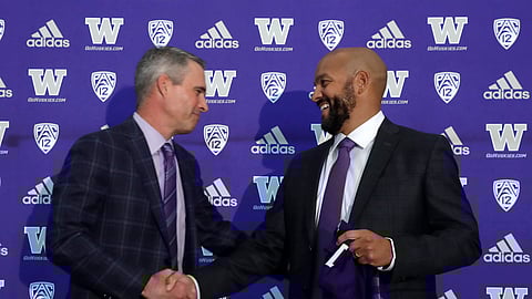 Washington NCAA college football head coach Chris Petersen, left, shakes hands with defensive coordinator Jimmy Lake following a news conference about Lake taking over the head coaching position, Tuesday, Dec. 3, 2019, in Seattle. Petersen unexpectedly resigned on Monday, a shocking announcement with the Huskies coming off a 7-5 regular season and bound for a sixth straight bowl game under his leadership. Petersen will coach Washington in a bowl game, his final game in charge. (AP Photo/Elaine Thompson)