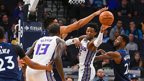 Sacramento Kings guard De'Aaron Fox (5) passes the ball to Kings center DeWayne Dedmon (13) as Minnesota Timberwolves center Karl-Anthony Towns tries to block the pass and Timberwolves forward Andrew Wiggins, right, looks on during the first half of an NBA basketball game Monday, Jan. 27, 2020, in Minneapolis. (AP Photo/Craig Lassig)