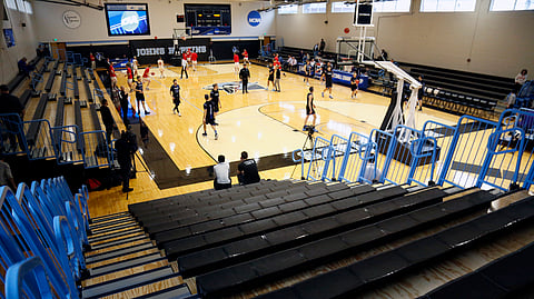 Yeshiva University players, foreground, warm up in a mostly empty Goldfarb Gymnasium at Johns Hopkins University before playing against Worcester Polytechnic Institute in a first-round game at the men's Division III NCAA college basketball tournament, Friday, March 6, 2020, in Baltimore, The university held the tournament without spectators after cases of COVID-19 were confirmed in Maryland. (AP Photo/Jessie Wardarski)