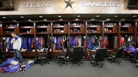 FILE - In this Oct. 11, 2016, file photo, Texas Rangers pitcher Sam Dyson, left, packs a bag in the locker room at the baseball park in Arlington, Texas. The NBA, NHL, Major League Baseball and Major League Soccer are closing access to locker rooms and clubhouses to all non-essential personnel in response to the coronavirus crisis, the leagues announced in a joint statement Monday, March 9, 2020. (AP Photo/LM Otero, File)