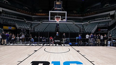 The seating area at Bankers Life Fieldhouse is empty as media and staff mill about, Thursday, March 12, 2020, in Indianapolis, after the Big Ten Conference announced that remainder of the men's NCAA college basketball games tournament was cancelled. (AP Photo/Michael Conroy)