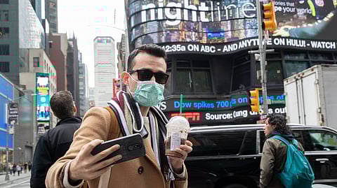 Justin Dalipi, of Albania, wears a mask as a precaution against the Corona virus during the final days of his visit to New York, as he takes a selfie in New York's Times Square, Tuesday, March 10, 2020.