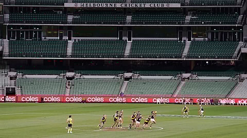 Players from Richmond and Carlton play their Australian Rules Football league game at an empty Melbourne Cricket Ground in Melbourne, Thursday, March 19, 2020, after bans on crowds of more than 500 assembling at outdoor venues amid the coronavirus pandemic. At the MCG less than two weeks ago, more than 86,000 people gathered to watch Australia beat India in the women's Twenty20 Cricket World Cup final.