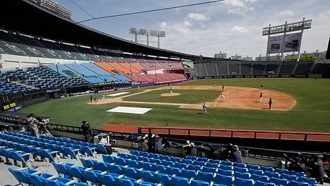 Photographers and TV camera work near empty seats during the pre-season baseball game between Doosan Bears and LG Twins in Seoul, South Korea, Tuesday, April 21, 2020. South Korea's professional baseball league has decided to begin its new season on May 5, initially without fans, following a postponement over the coronavirus.