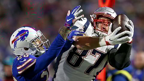 In this Oct. 29, 2018, file photo, New England Patriots tight end Rob Gronkowski, right, makes a catch next to Buffalo Bills defensive back Phillip Gaines during the second half of an NFL football game in Orchard Park, N.Y. Gronkowski, the retired Patriots tight end, is set to host WrestleMania in April from WWE's performance center.