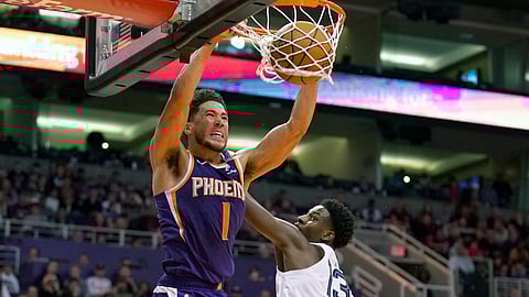 In this Jan. 5, 2020, file photo, Phoenix Suns guard Devin Booker (1) dunks over Memphis Grizzlies forward Jaren Jackson Jr. in the second half of an NBA basketball game in Phoenix. Booker won the NBA 2K20 Players Tournament on Saturday, April 11, 2020, sweeping Suns teammate Deandre Ayton in the best-of-three final.