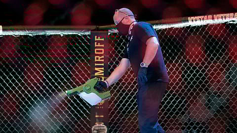 A worker sprays sanitizer in the octagon between bouts during a UFC 249 mixed martial arts competition, Saturday, May 9, 2020, in Jacksonville, Florida.