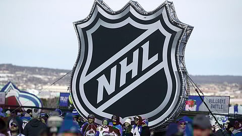 In this Saturday, Feb. 15, 2020, file photo, fans pose below the NHL league logo at a display outside Falcon Stadium before an NHL Stadium Series outdoor hockey game between the Los Angeles Kings and Colorado Avalanche, at Air Force Academy, Colo. The NHL Players’ Association’s executive board is voting on a 24-team playoff proposal as the return-to-play format, a person with knowledge of the situation told The Associated Press, late Thursday, May 21, 2020.