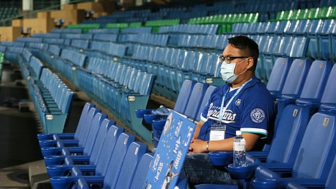 In this Friday, April 24, 2020, photo, a staff member of Chinatrust Brothers sits on the stands during a game against Fubon Guardians with no audience at Xinzhuang Baseball Stadium in New Taipei City, Taiwan, Friday, April 24, 2020. Taiwan has relatively few cases of COVID-19, so the league decided it was safe to let in players, coaches, cheerleaders, costumed mascots, face mask-wearing batboys and the media.