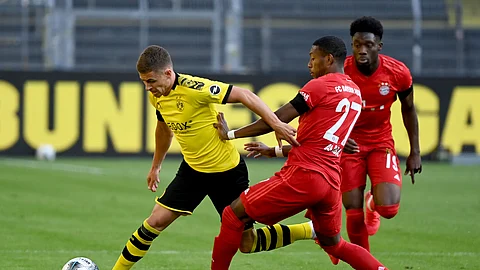 Munich's David Alaba, center, and Alphonso Davies, right, challenge for the ball with Dortmund's Thorgan Hazard, left, during the German Bundesliga soccer match between Borussia Dortmund and FC Bayern Munich in Dortmund, Germany, Tuesday, May 26, 2020. The German Bundesliga is the world's first major soccer league to resume after a two-month suspension because of the coronavirus pandemic. (Federico Gambarini/DPA via AP, Pool)