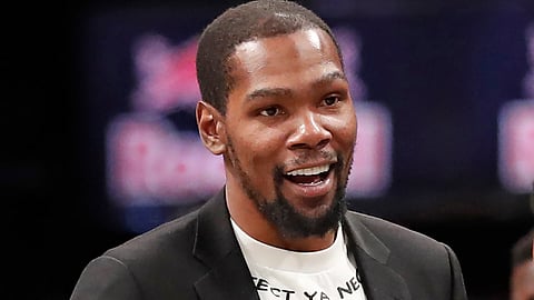 In this Dec. 26, 2019, file photo, injured Brooklyn Nets player Kevin Durant smiles as he greets teammates returning to the bench during a timeout in the second half of an NBA basketball game against the New York Knicks, in New York.