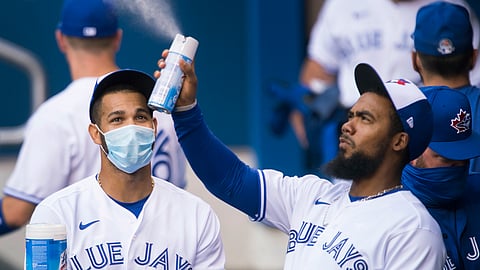Toronto Blue Jays left fielder Lourdes Gurriel Jr., left, watches teammate Teoscar Hernandez, right, spray sanitizer in the dugout during the first inning of an intersquad baseball action in Toronto on Friday, July 17, 2020. The Blue Jays have been denied approval by the Canadian government to play in Toronto amid the coronavirus pandemic. Mark Eckel thinks the homeless Blue Jays won't be able to muster 28 wins this season.
