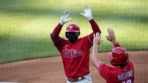Philadelphia Phillies' Didi Gregorius celebrates without touching, while wearing a mask, his three-run homer with Rhys Hoskins during the first inning of an exhibition baseball game against the Washington Nationals at Nationals Park, Saturday, July 18, 2020, in Washington.