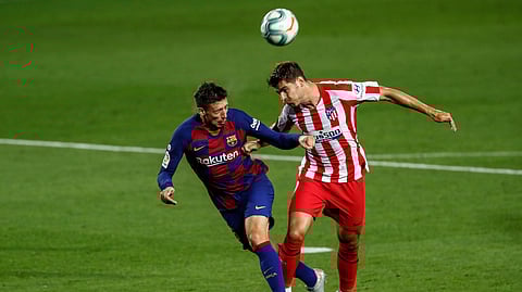 Barcelona's Clement Lenglet, left, and Atletico Madrid's Alvaro Morata jump for the ball during the Spanish La Liga soccer match between FC Barcelona and Atletico Madrid at the Camp Nou stadium in Barcelona, Spain, Tuesday, June 30, 2020.