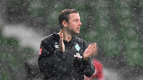 Bremen's head coach Florian Kohfeldt encourages his team under heavy rain during the German Bundesliga soccer match between Werder Bremen and Bayern Munich in Bremen, Germany, Tuesday, June 16, 2020. Because of the coronavirus outbreak all soccer matches of the German Bundesliga take place without spectators.