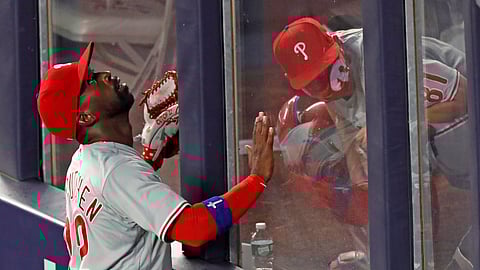 Philadelphia Phillies left fielder Andrew McCutchen (22) tracks the path of Gio Urshela's sixth-inning, three-run home run as Phillies catrching coach Greg Brodzinski ducks in the bullpen in a baseball game against the New York Yankees, Monday, Aug. 3, 2020, at Yankee Stadium in New York.