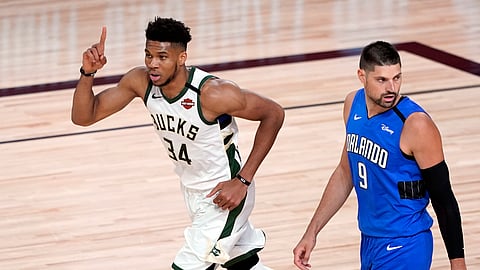 Milwaukee Bucks' Giannis Antetokounmpo (34) celebrates after a dunk as Orlando Magic's Nikola Vucevic (9) looks back during the first half of an NBA basketball first round playoff game Saturday, Aug. 29, 2020, in Lake Buena Vista, Fla.