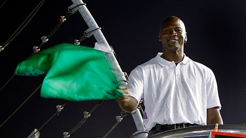 In this May 22, 2010, file photo, Charlotte Bobcats owner Michael Jordan practices waving the green flag before a NASCAR All-Star auto race at Charlotte Motor Speedway in Concord, N.C. Denny Hamlin is starting his own race car team in partnership Jordan and Bubba Wallace as the driver.