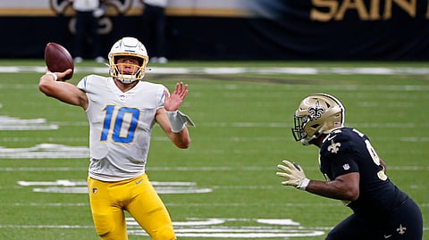 Los Angeles Chargers quarterback Justin Herbert (10) passes under pressure from New Orleans Saints defensive end Cameron Jordan (94) in the first half of an NFL football game in New Orleans, Monday, Oct. 12, 2020.