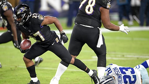 Baltimore Ravens running back J.K. Dobbins, left, gets by the tackle attempt of Dallas Cowboys strong safety Darian Thompson while scoring a touchdown during the second half of an NFL football game, Tuesday, Dec. 8, 2020, in Baltimore.