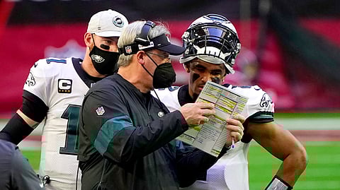 Philadelphia Eagles head coach Doug Pederson talks with starting quarterback Jalen Hurts as quarterback Carson Wentz (11) looks on during the first half of an NFL football game, Sunday, Dec. 20, 2020, in Glendale, Ariz.