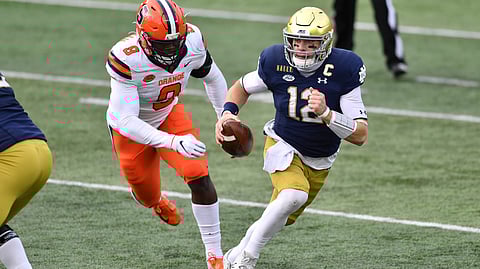 Notre Dame quarterback Ian Book (12) runs as Syracuse defensive lineman Jonathan Kingsley (9) pursues in the first half of an NCAA college football game Saturday, Dec. 5, 2020, in South Bend, Ind.