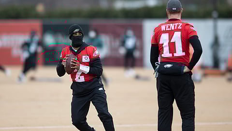 Eagles quarterback Jalen Hurts (left) throws during practice Wednesday as Carson Wentz looks on