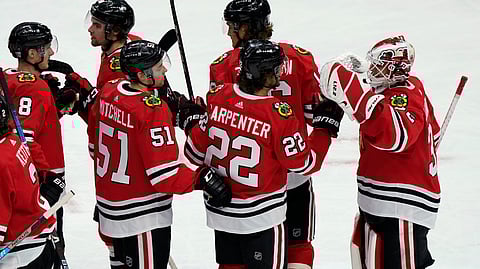 Chicago Blackhawks goalie Kevin Lankinen, right, celebrates with teammates after the team's 4-1 win over the Detroit Red Wings in an NHL hockey game in Chicago, Friday, Jan. 22, 2021.