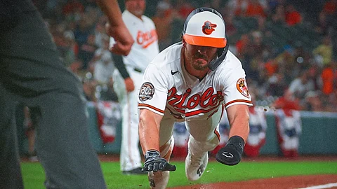 Ryan McKenna of the Baltimore Orioles dives head first for home.