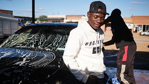 Brighton Moyo with a newly acquired BMW bought from gold proceeds at a car wash in Filabusi, a town in southern Zimbabwe.