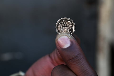 Close-up of a person holding a one South African rand coin.