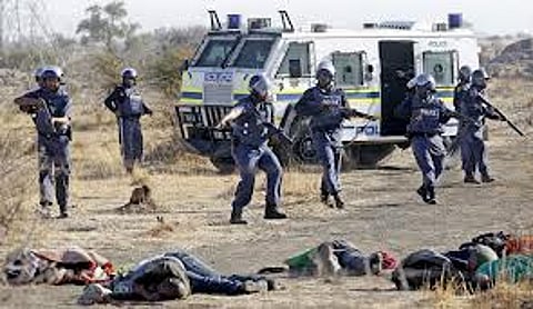Policemen keep watch over striking miners after they were shot outside Lonmin's Marikana mine 100 km (62 miles) northwest of Johannesburg, in this August 16, 2012 file photo. South Africa's President Jacob Zuma will on June 25, 2015 release a report into the 2012 shooting of 34 striking miners at the mine, the government said in a statement. Zuma received the results in March of a nearly three-year inquiry by retired judge Ian Farlam into the "Marikana massacre". Picture taken August 16, 2012. REUTERS/Siphiwe Sibeko/Files