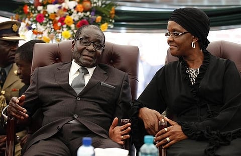 Zimbabwe President Robert Mugabe (L) speaks to his wife Grace during the funeral of his sister, Bridget, in the village of Zvimba, 90 km (55 miles) west of Harare January 21 2014. REUTERS/Philimon Bulawayo