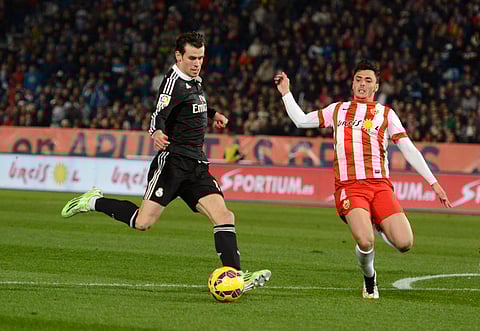 Real Madrid's Gareth Bale (L) kicks the ball next to Almeria's Ximo Navarro during their Spanish First Division soccer match at Juegos Mediterraneos stadium in Almeria December 12, 2014. REUTERS/Francisco Bonilla