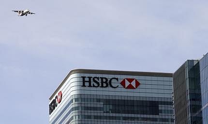 A plane flies past the HSBC building in Canary Wharf, London April 17, 2015.  HSBC and Standard Chartered are looking at the viability of quitting London for a new home in Asia because a big jump in a tax on UK banks makes staying in Britain increasingly painful. Several investors told Reuters they want the two banks to do a thorough analysis on whether it makes sense to move after Britain raised the bank tax by a third last month. REUTERS/Cathal McNaughton