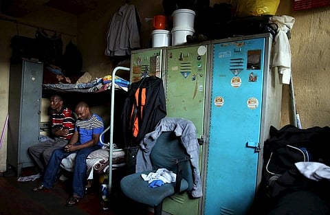 Zakhele Ntsele (L) sits on a bed with a friend in a room he shares with fourteen other men at Jeppestown men's hostel in Johannesburg May 19, 2015. Grim, mainly single-sex dormitory blocks dotted round South Africa's main cities, the hostels are one of the lesser-known legacies of apartheid and the migrant labour system enforced on blacks by the white minority rule that ended two decades ago. Associated with Dickensian poverty, crime and, in many cases, Zulu tribalism - they played a major role in the wave of anti-foreigner violence last month in which at least seven people were killed. Picture taken May 19, 2015. REUTERS/Siphiwe Sibeko