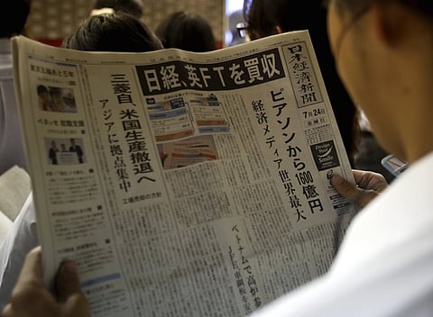 A man reads the front page of Japan's Nikkei newspaper reporting Japanese media group Nikkei's acquisition of the Financial Times from Britain's Pearson at a train station in Tokyo, Japan, July 24, 2015. Japanese media group Nikkei has agreed to buy the Financial Times from Britain's Pearson for $1.3 billion, putting one of the world's premier business newspapers in the hands of a company influential at home but little known outside Japan. REUTERS/Yuya Shino