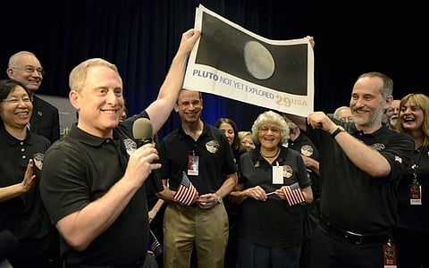 NASA Principal Investigator for New Horizons mission Alan Stern (L) and Co-Investigator Will Grundy (R) hold up an enlarged, out-dated U.S. postage stamp with the words "PLUTO NOT YET EXPLORED", during the celebration of the spacecraft New Horizons flyby of Pluto, at NASA's Johns Hopkins Applied Physics Laboratory in Laurel, Maryland, July 14, 2015. Also attending are APL Director Ralph Semmel (center,L) and Annette Tombaugh, daughter of Pluto's discoverer Clyde Tombaugh (center,R). The flyby, which culminated after almost ten years of flight and over three billion miles, will allow New Horizons to photograph and collect data in the coming months.     REUTERS/Mike Theiler