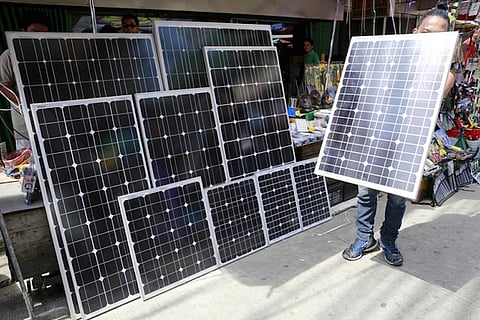 A vendor holds a piece of solar panel to attract buyers at a stall in Manila July 13, 2015. Solar companies will push the Philippine government to quadruple the size of an incentive scheme for suppliers of the renewable energy and to speed up project approvals, as the country grapples with precarious electricity supply. REUTERS/Romeo Ranoco