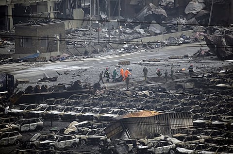 Firefighters walk among debris as they carry out the body of a victim from the site of the explosions towards an ambulance at the Binhai new district, Tianjin, China, August 14, 2015. Several Japanese automakers including Toyota Motor Corp reported damage to cars and facilities after two huge explosions at the Chinese port of Tianjin tore through an industrial area where toxic chemicals and gas were stored. REUTERS/Jason Lee