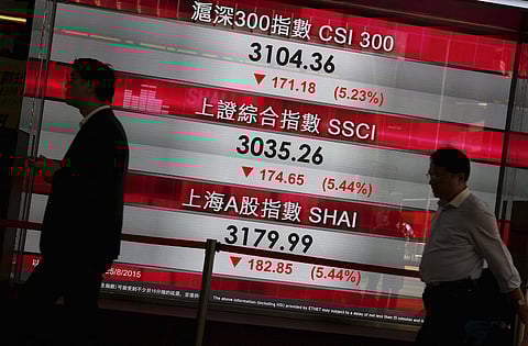 Passers-by walk past a panel displaying falling China stock indexes, at the financial Central district in Hong Kong, China August 25, 2015. China's major stock indexes slumped more than 6 percent to 8-month lows in early trade on Tuesday before paring losses, after a catastrophic Monday that destabilised financial markets around the world. REUTERS/Bobby Yip
